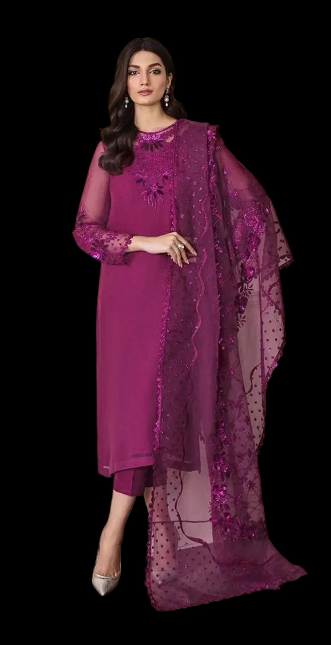 A woman models a traditional Indian outfit consisting of a magenta kurta, matching trousers, and a sheer embroidered dupatta, set against an indoor wall background.