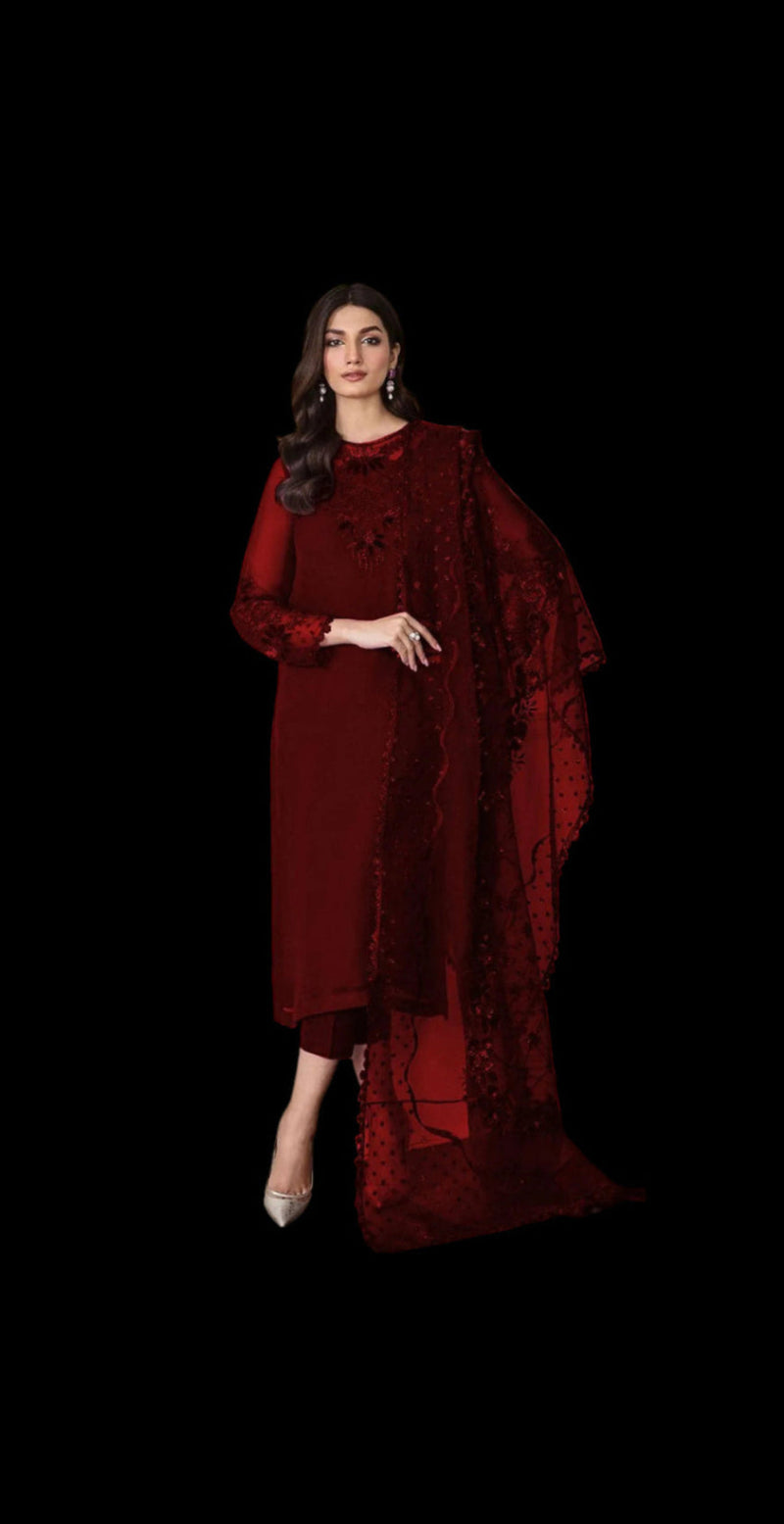 Woman wearing a red embroidered outfit against a white wall