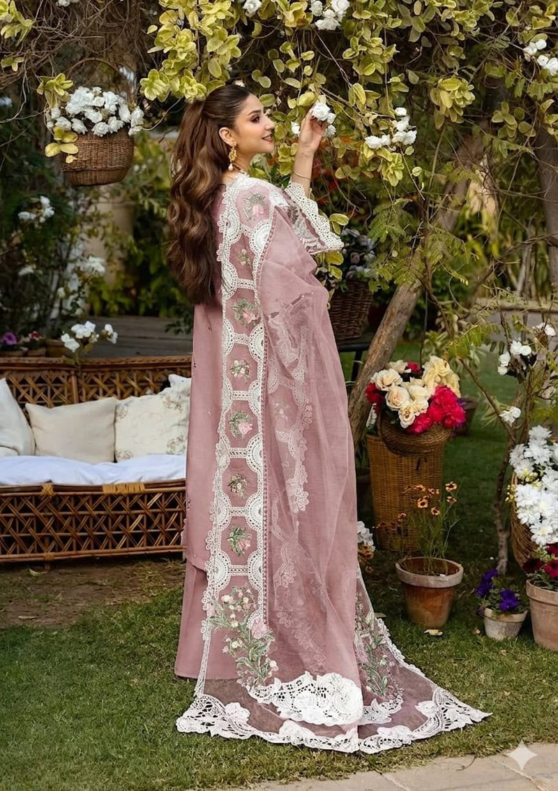 Woman in a pink and white embroidered traditional outfit standing in a garden with flowers and furniture.